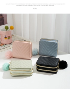 Detail view of double-zippered leather wallets with V-quilted stitching and plush pom charms
