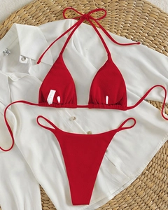 Close-up of red ribbed halter bikini set with tie details on a textured beach mat