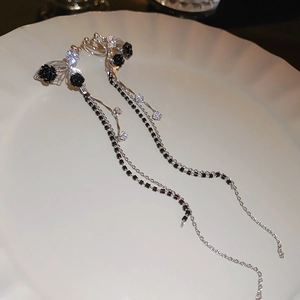 Detail of silver long tassel earrings featuring black rose and butterfly with zircons
