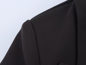Close-up of shoulder seam and woven fabric texture on a black double-breasted blazer