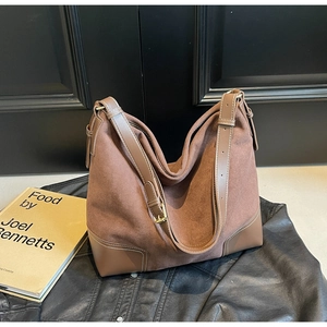 Retro large brown suede tote bag with wide strap and golden buckles on a leather surface