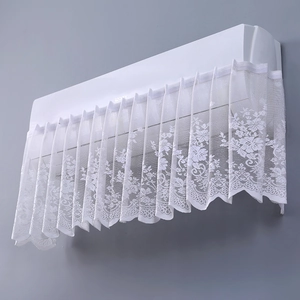 Detail of white lace air conditioner cover featuring delicate hollow floral patterns
