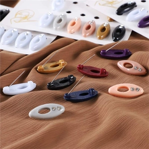 Colorful oval plastic hijab pins with rhinestones set on brown pleated fabric