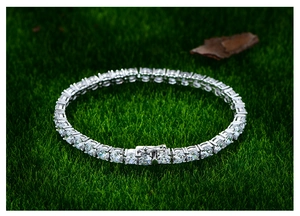 Makro-Detail des silbernen Tennisarmbands mit funkelnden runden Kristallen auf Gras