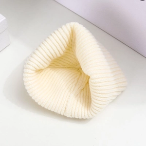 Close-up of ivory knitted beanie showing detailed ribbed texture and soft wool fabric