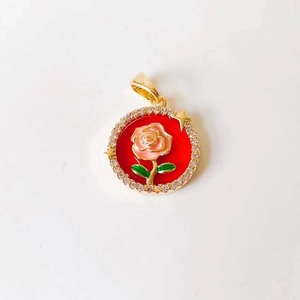 Macro shot of gold rose pendant with red enamel and pavé zircon stones details