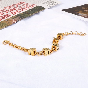 Titanium steel Lucky cube charm bracelet with golden finish on white fabric backdrop