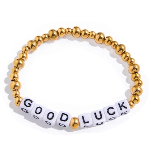 Macro shot of gold metal beads and white square letter beads spelling GOOD LUCK