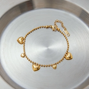 Detail view of 18k gold-plated stainless steel bead bracelet with five heart charms