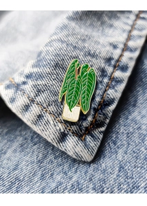 Detailed close-up of a green plant enamel pin on a blue denim jacket collar