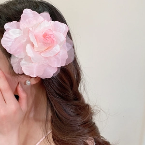Gros plan d'une élégante pince à cheveux fleur en maille rose sur cheveux ondulés.