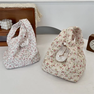 Detailed view of floral canvas wrist bags with white lace trim and rustic prop decor