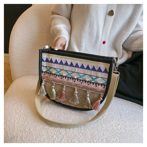 Detail of bohemian cross-body bag featuring geometric embroidery and colorful tassels