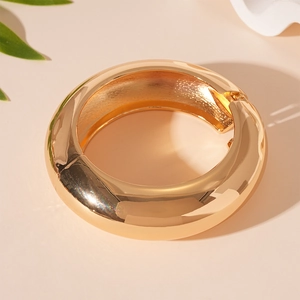 Macro shot of gold polished wide band geometric hinge bracelet with glossy metallic finish