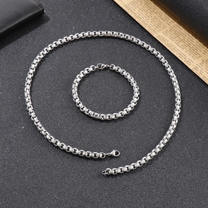 Silver mesh chain necklace and bracelet set with lobster clasp on a dark textured surface