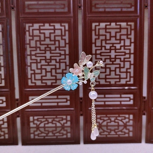 Detailed close-up of golden butterfly hair stick with pearl tassels and enamel flowers