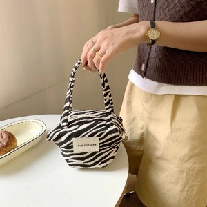 Detail of zebra print canvas tote bag featuring double handles and a woven logo label