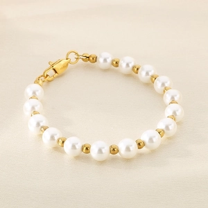 Macro view of white freshwater pearls with golden spacers and a secure lobster clasp