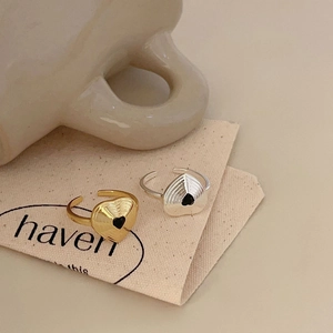Close-up of gold and silver heart-shaped open rings with radial texture and black heart detail