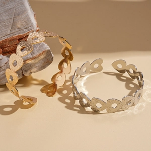 Bracciali aperti a cuore in oro e argento con texture metallica su base di roccia