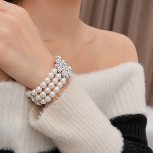 Detail of multi-layer pearl bracelet with a large rhinestone butterfly clasp on wrist