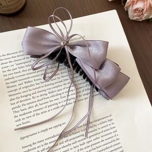 Detail of a purple satin layered bow hair clip with rhinestone and elegant long ribbons