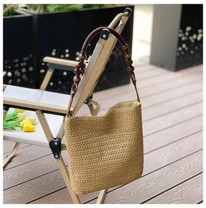 Detail of hand-woven straw shoulder bag with decorative wooden beads and rustic texture