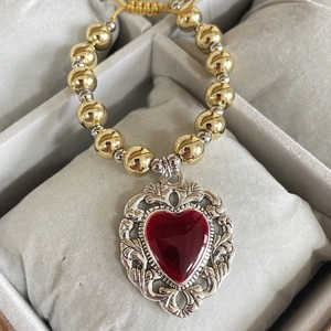 Detailed shot of retro gold beads and red enamel heart pendant in a jewelry tray