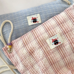Detailed macro view of trendy drawstring canvas backpacks with blue and red plaid textures