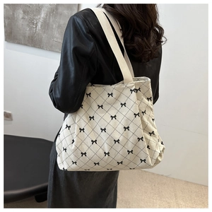 Close-up of off-white corduroy tote bag with black bow and diamond pattern