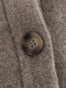 Close-up of camel knit texture and detailed button on women's cardigan sweater