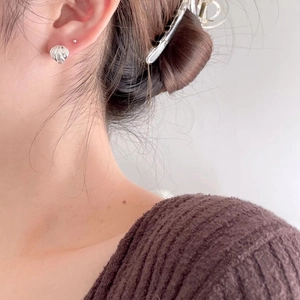Detail of 925 sterling silver geometric shell texture earrings worn on model's ear