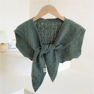 Dark green hollow-out knitted shawl draped over a wooden hanger with tie-knot detail