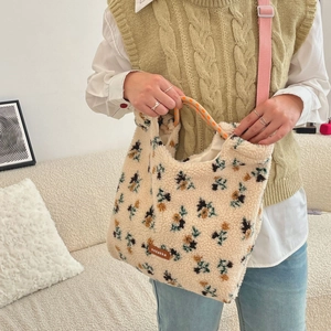 Detail of pixelated floral plush tote bag with orange checkered handles and sozakka label