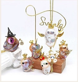 Detail of baroque pearl pendants with gold monster and witch hat charms on stands