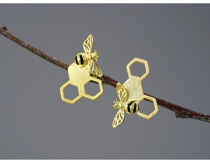 Macro shot of 925 silver honeycomb bee earrings hanging on a natural tree branch