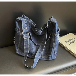 Vue détaillée du sac cabas en jean bleu foncé avec bords effilochés et bandoulière