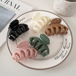 Set of five elegant glossy shark hair claws in assorted colors on a ceramic tray