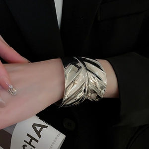 Gros plan sur un large bracelet manchette argenté avec texture ondulée irrégulière