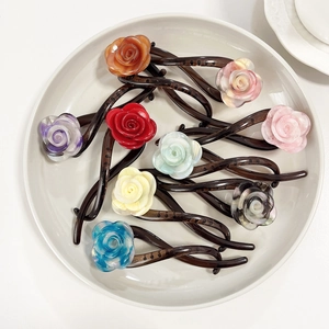 Set of 10 acetate rose flower hair clips in various colors on a white ceramic plate