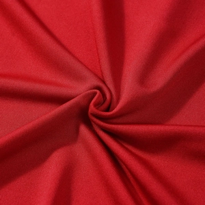Macro detail of red stretch knit fabric texture showing fine twill weaving and soft drape