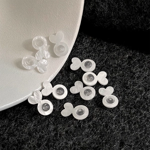 Macro detail of white pearlescent fish-shaped silicone earring back stoppers