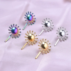 Detail of sunburst earrings in silver, gold, and iridescent finishes on purple silk