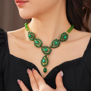 Nahaufnahme einer Vintage Goldhalskette mit grünen Edelsteinen und Strass an einem Modell