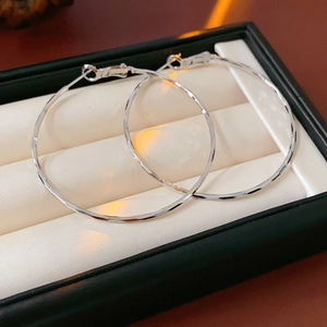 Gros plan détaillé de créoles en argent avec texture martelée dans un écrin à bijoux