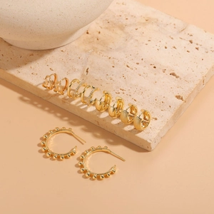 Detailed close-up of 14K gold-plated heart earrings with zircon inlay on a stone base