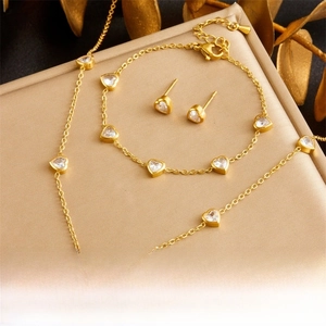 Gold-plated jewelry set with heart-shaped transparent stones on satin backdrop