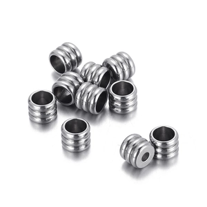 Set of ten silver stainless steel cylindrical beads with three grooves on white background
