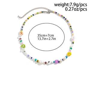 Close-up of handmade colorful daisy seed bead necklace with imitation pearls and letter F