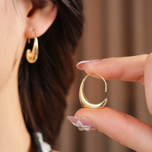 Close-up of sleek 14k gold-plated oval hoop earrings showing smooth polished texture